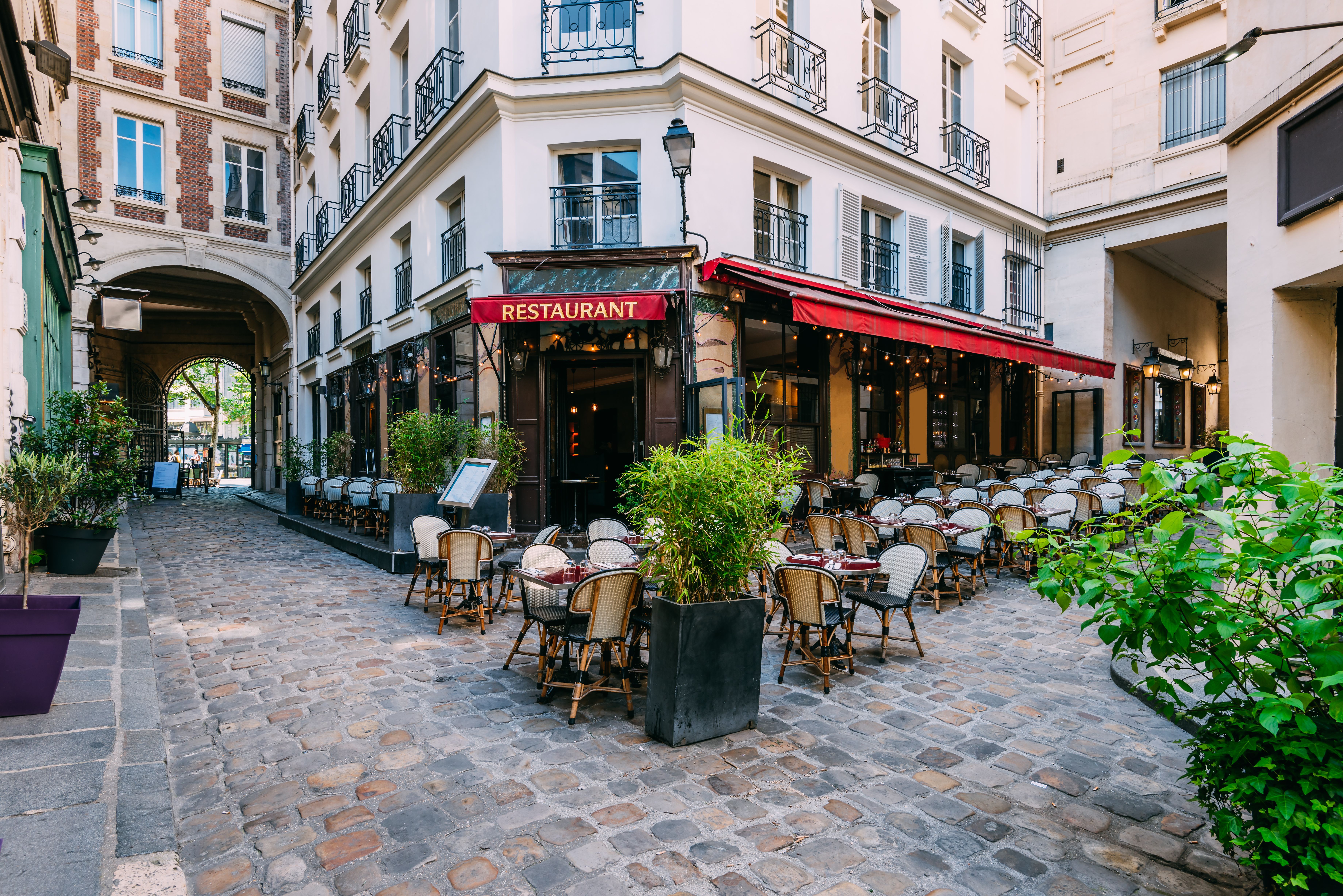 View of a restaurant in Paris tucked in a street courtyard with outdoor tables and chairs