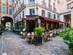 View of a restaurant in Paris tucked in a street courtyard with outdoor tables and chairs