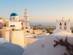 Sunset views over a whitewashed, blue-domed church; church bells and a tall tower in Santorini