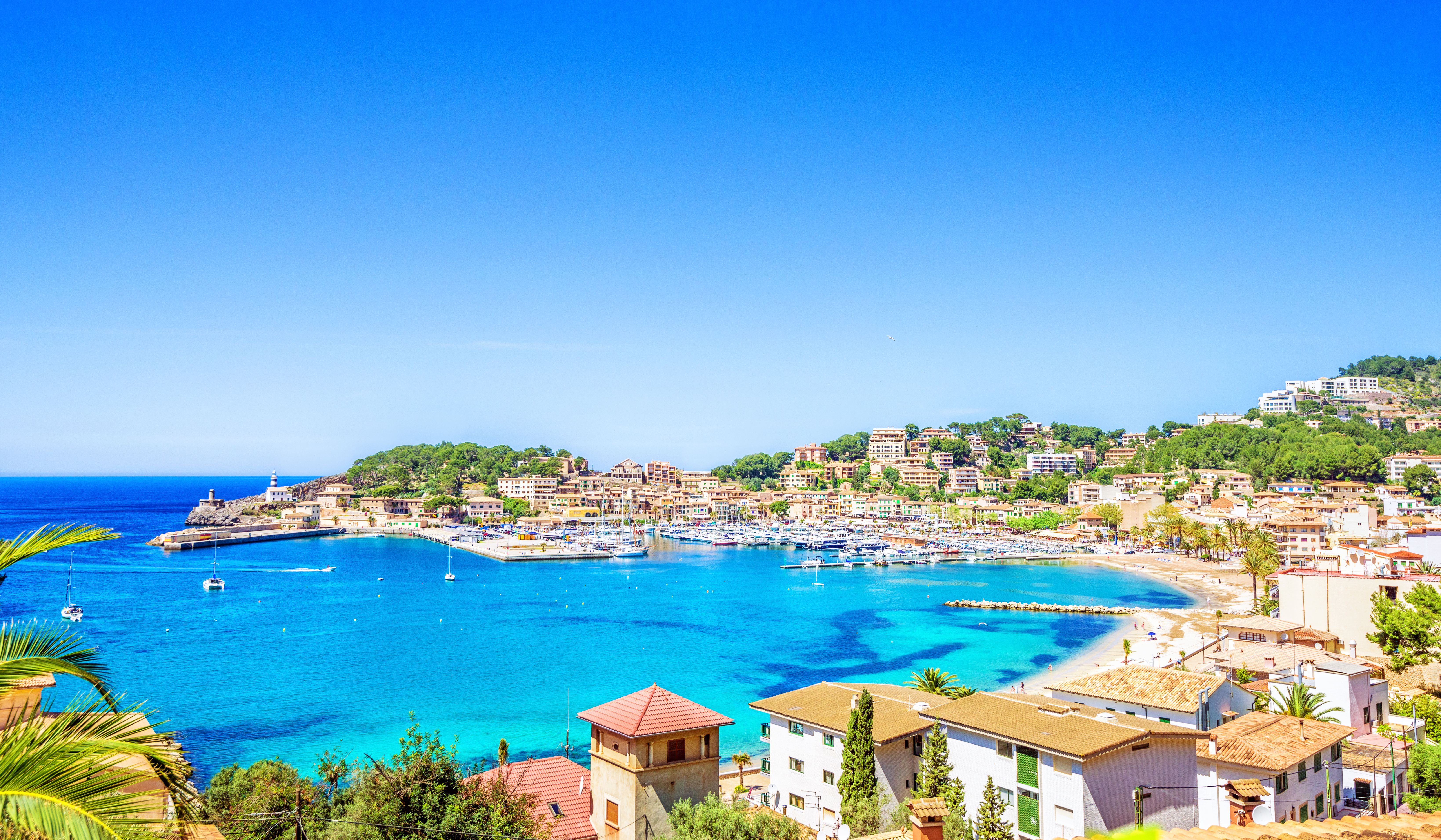An aerial view over the harbour and beach of the resort town of Puerto de Soller in Majorca with clear blue sky