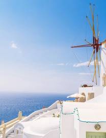 Close photo of a wood-and-white windmill overlooking the Mediterranean in Santorini