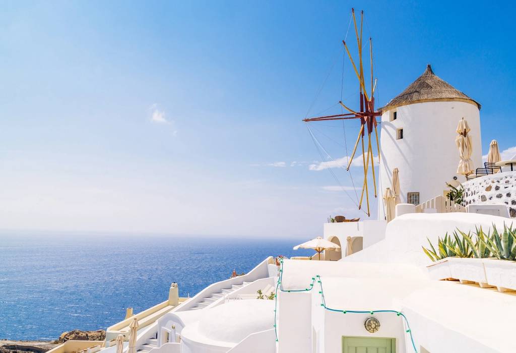 Close photo of a wood-and-white windmill overlooking the Mediterranean in Santorini