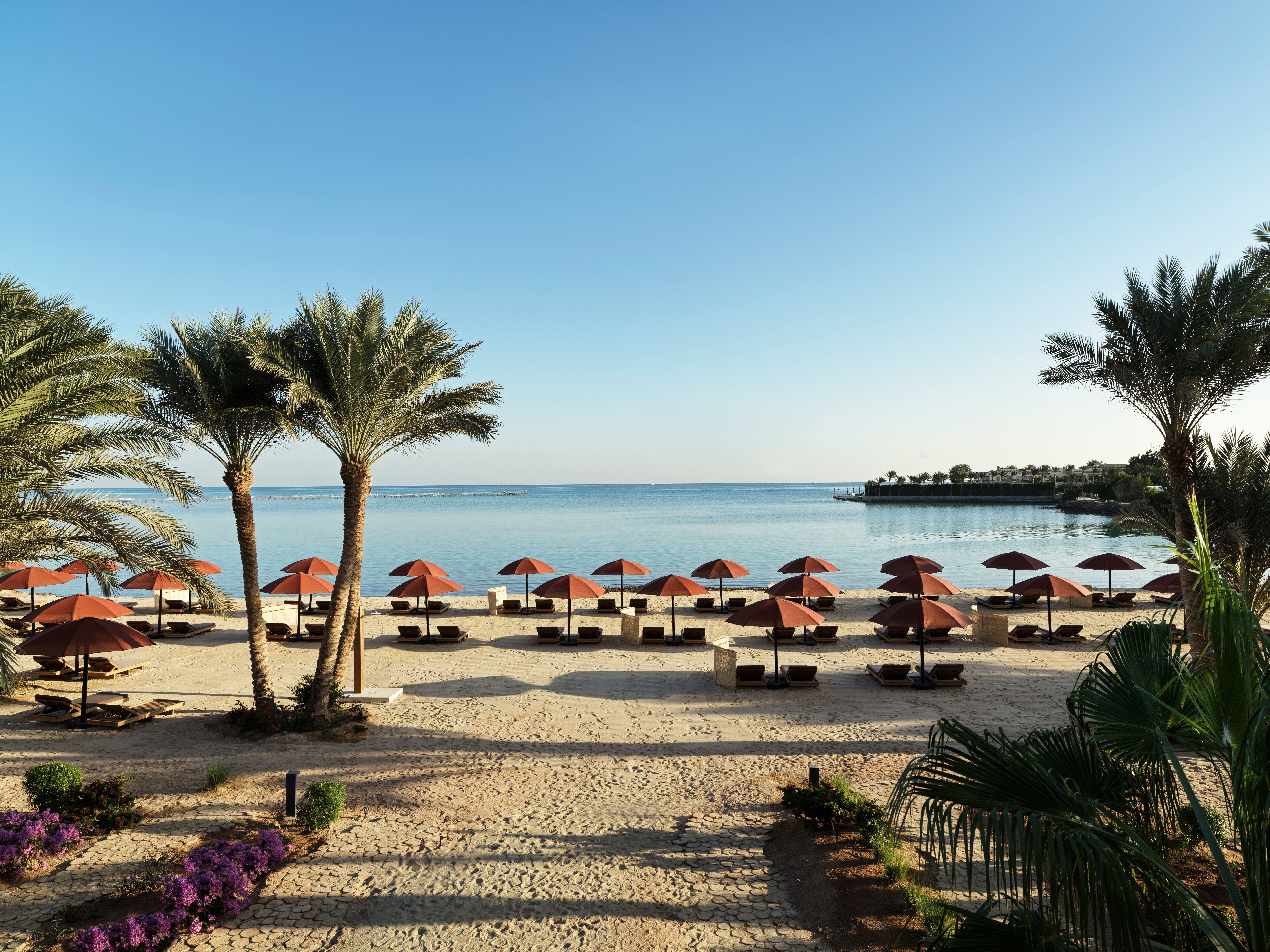 View of The Chedi Hotel private beach with palm trees and sun-loungers in El Gouna, Egypt