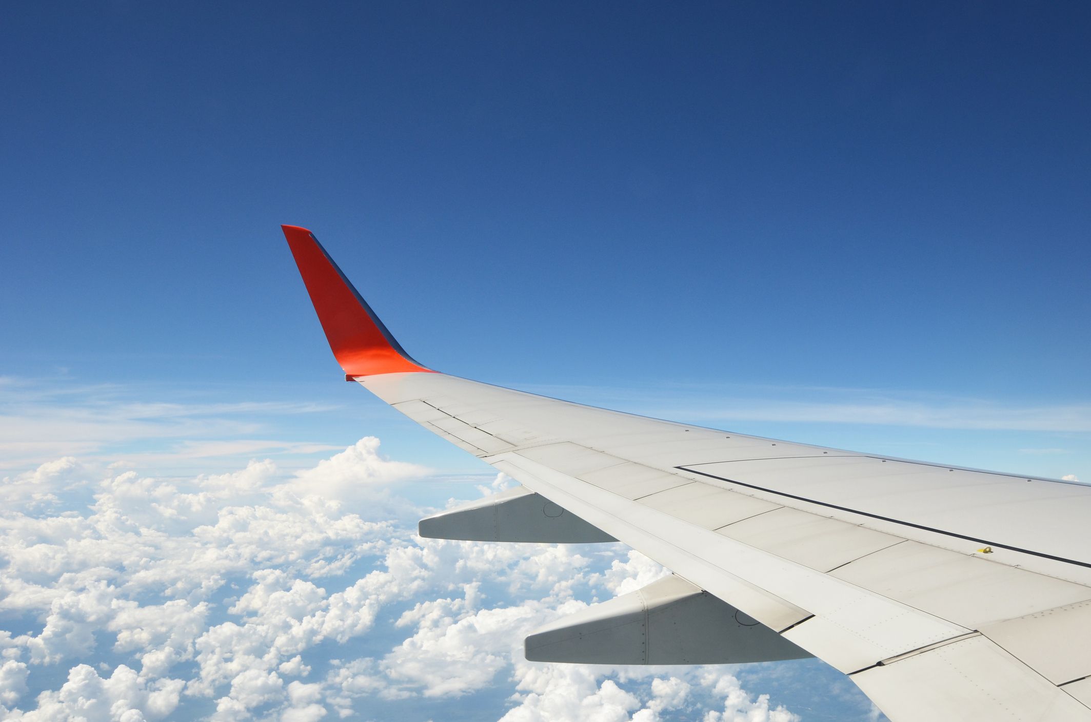 A view of a plane wing above a cloudy sky