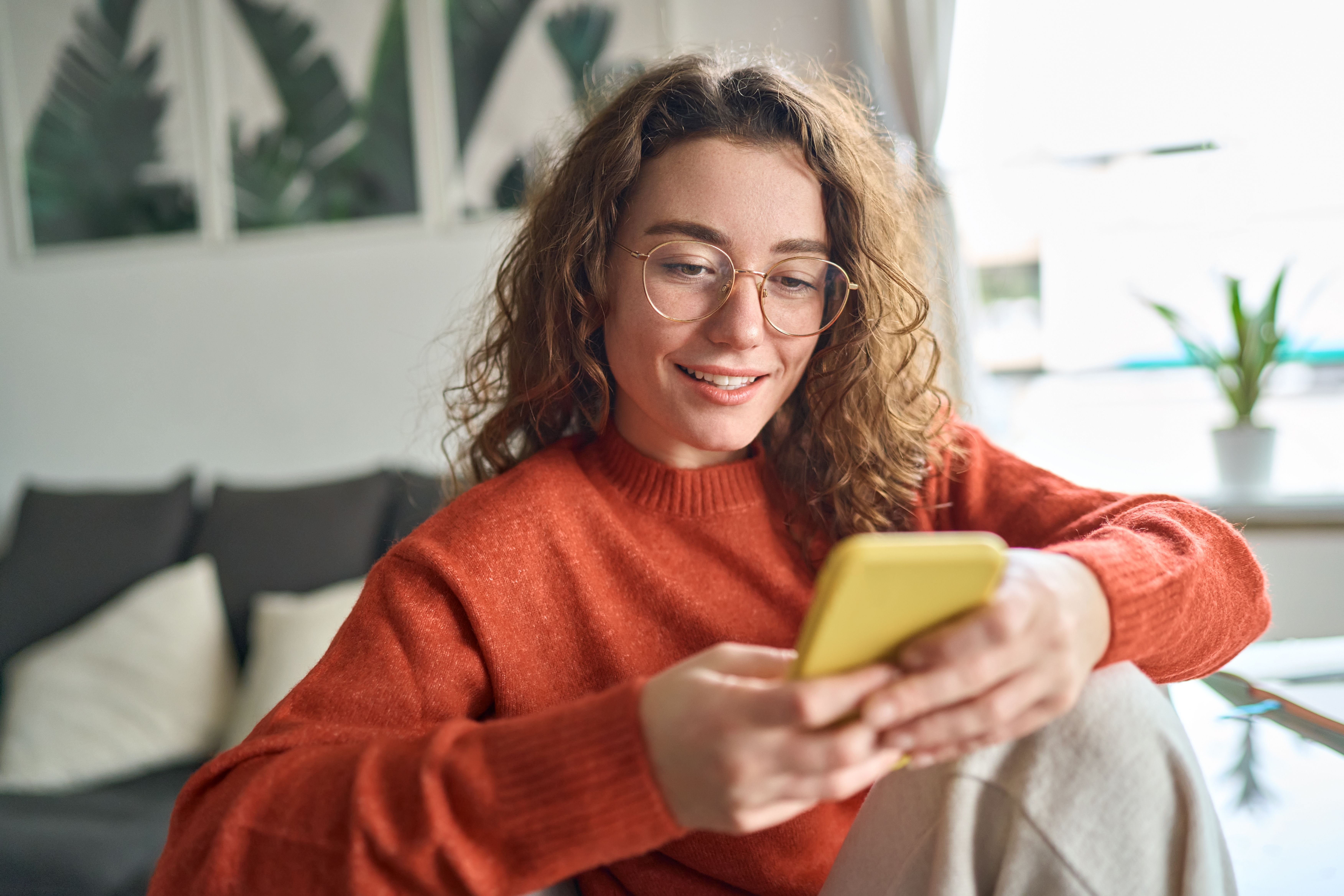A smiling woman looking at her phone