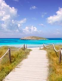 Wooden boardwalk leading to the white sands and blue waters of Illetes Beach in Formentera