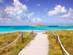 Wooden boardwalk leading to the white sands and blue waters of Illetes Beach in Formentera