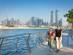 A mother and daughter walk along the Dubai canal with the city's famous skyscrapers in the background