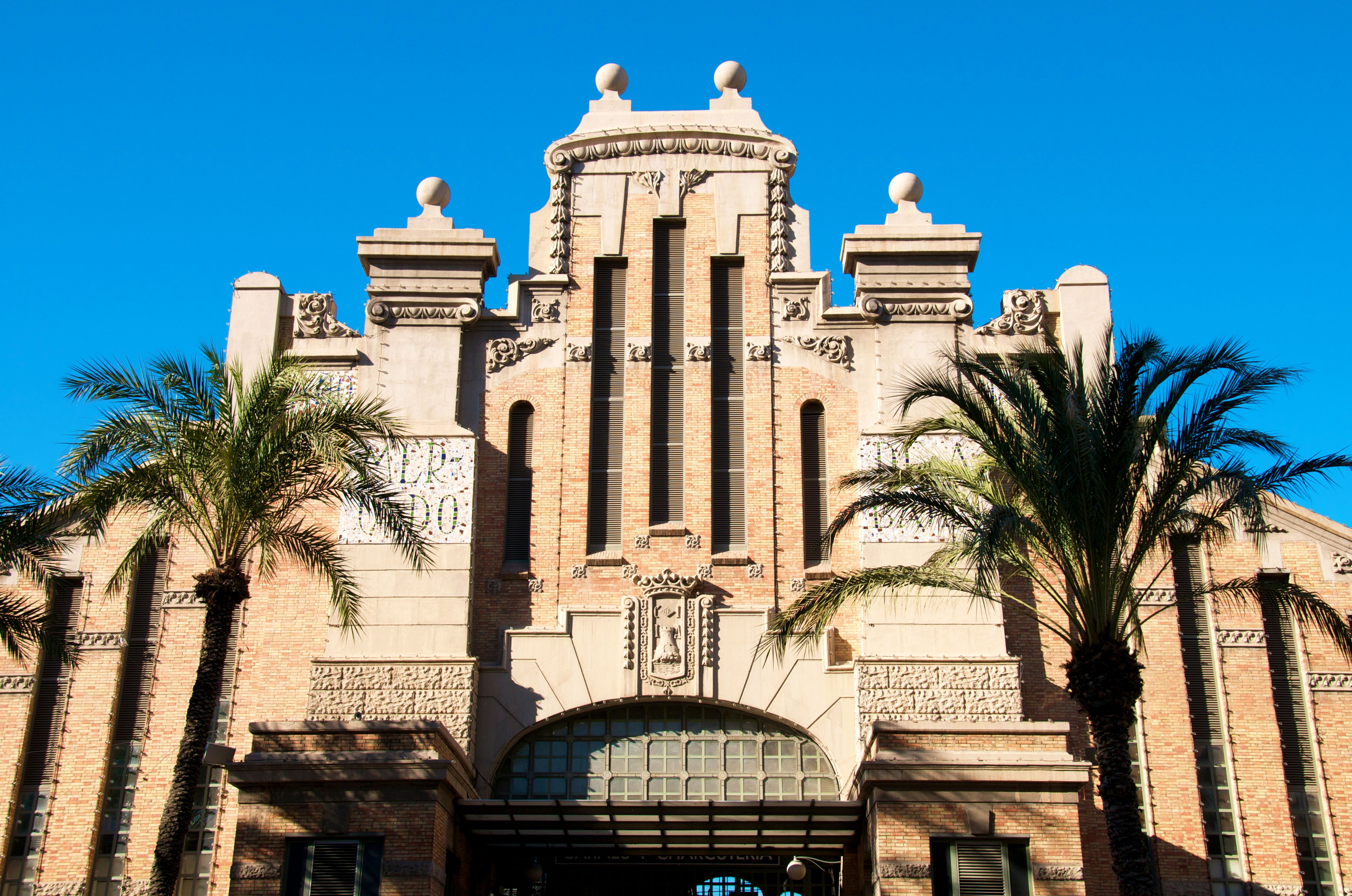 View of the sandstone, art deco facade of a food and produce market in Alicante.