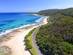Aerial view of a winding road that hugs the south coast of Australia with bush on the right side and a golden beach to the left
