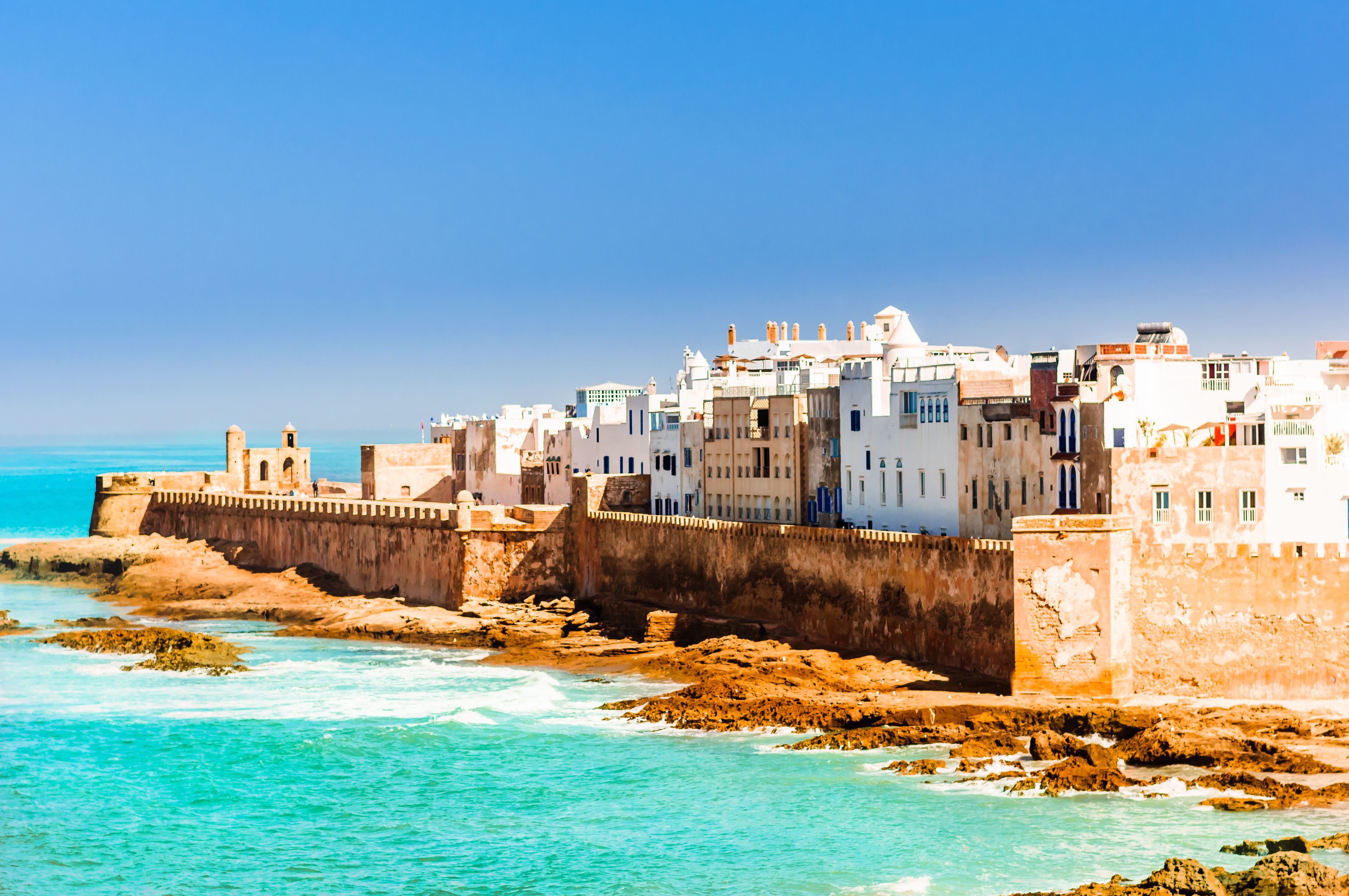 View of white and beige houses along a high fortified sea wall in Essaouira