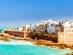 View of white and beige houses along a high fortified sea wall in Essaouira
