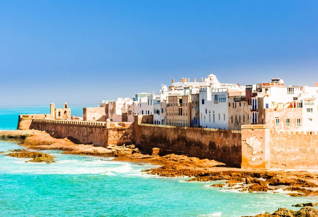 View of white and beige houses along a high fortified sea wall in Essaouira