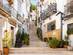 A view of a stepped back street in Alicante old town, lined wither side with white houses with black metal balconies