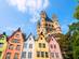 Looking up at pastel coloured houses and the tower of a church on a sunny day in Cologne