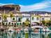 The traditional white buildings with colourful trim in Puerto de Mogan, with boats moored in the front and a backdrop of mountains