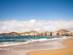 View of waves crashing on the golden sands of Las Canteras beach with the low-rise apartments of the city in the background