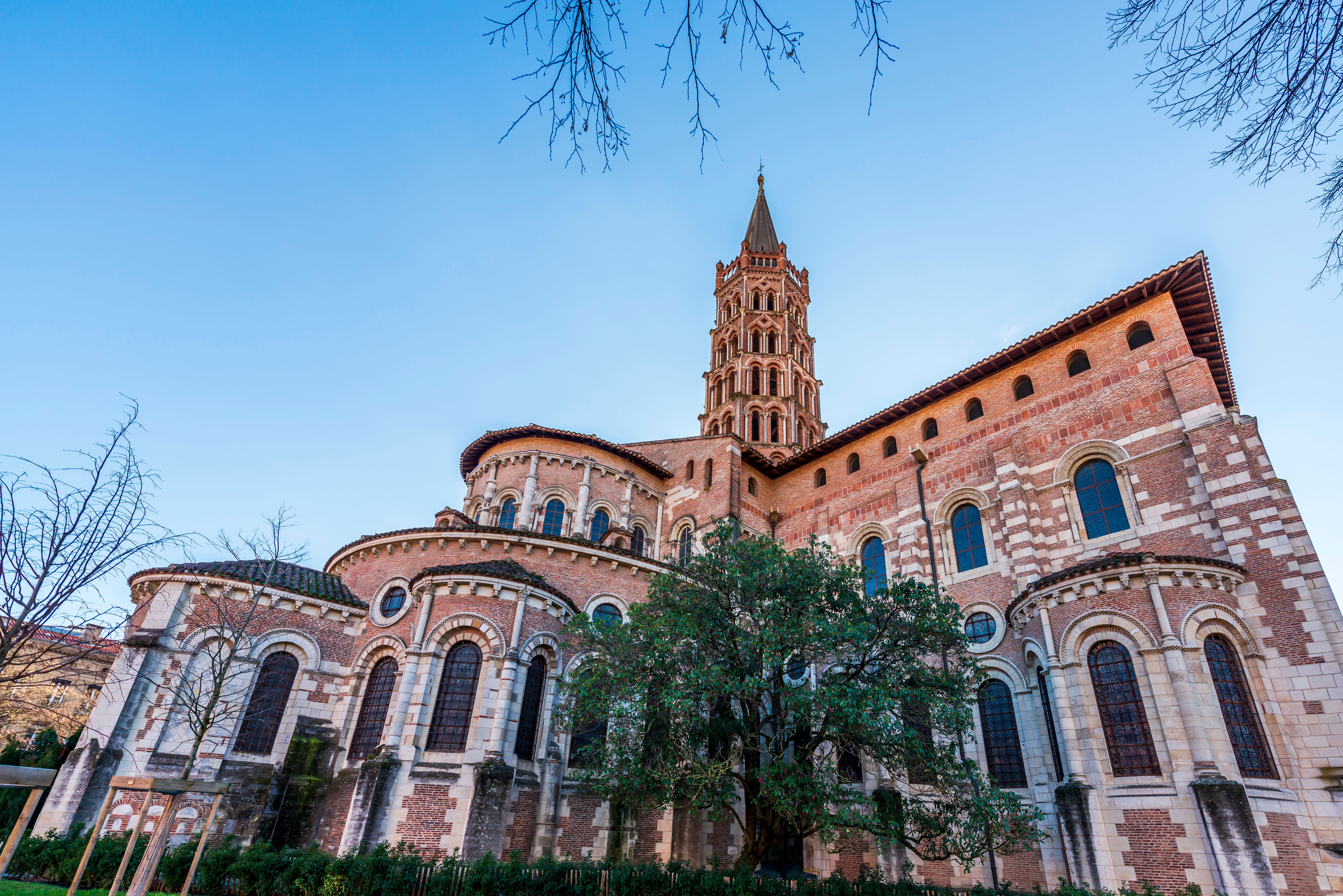 View of a pink brick church with a tall, windowed bell tower.