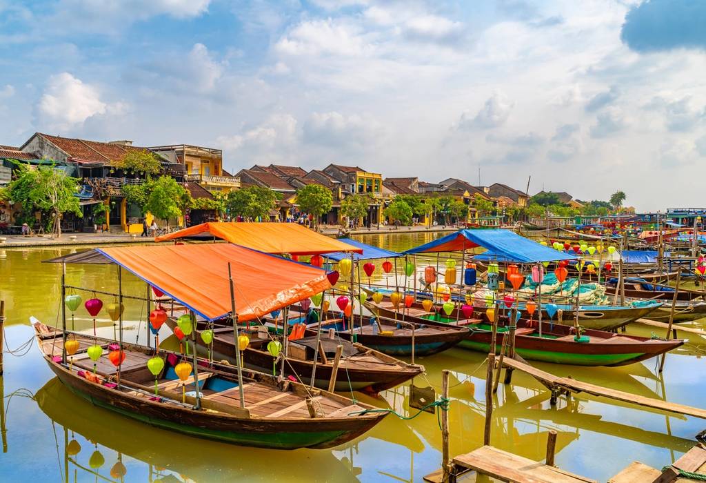 A view of traditional wooden boats with colourful lanterns on the Thu Bon River in Hoi An, Vietnam