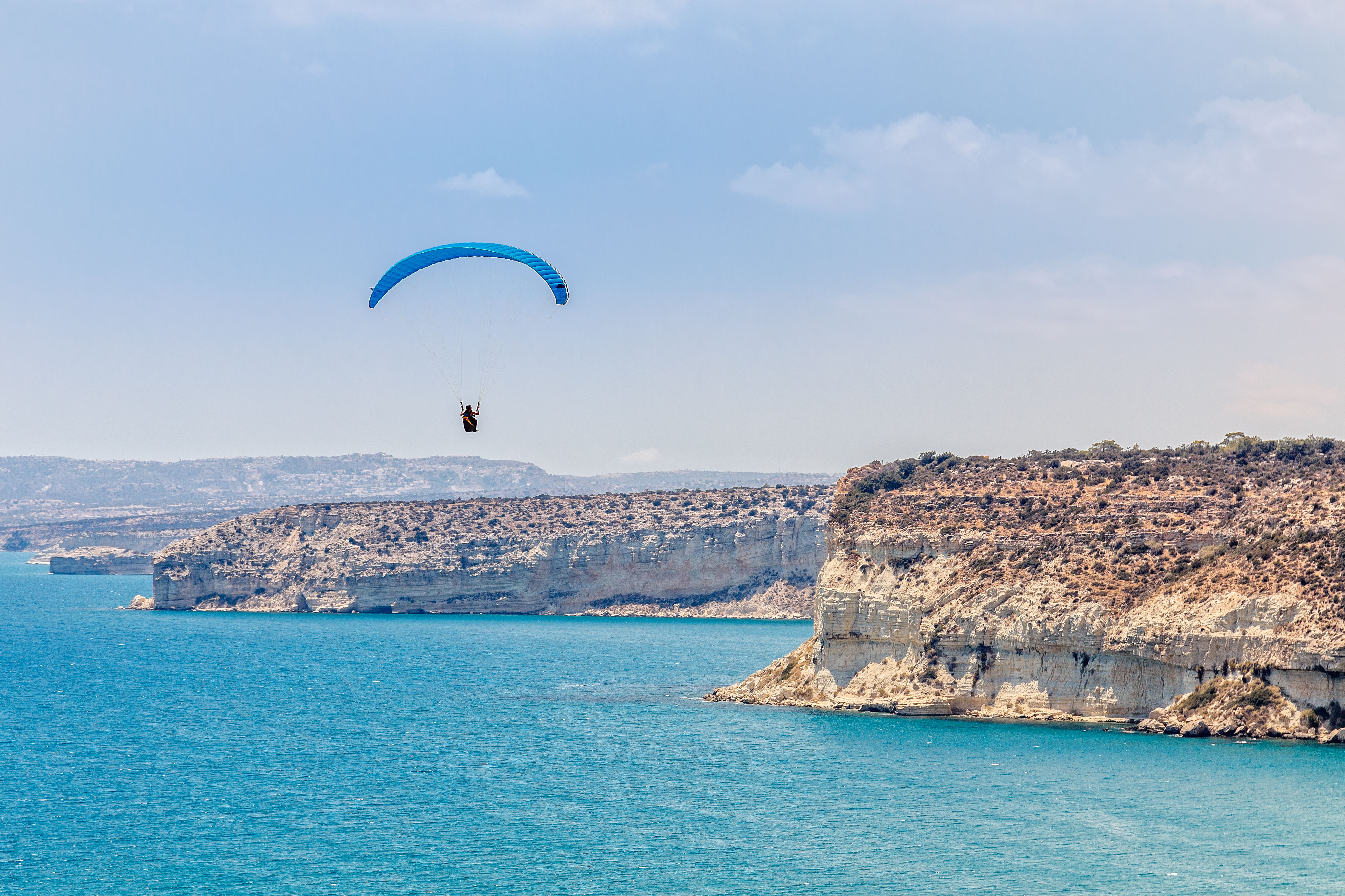 Paraglider soaring over the cliffs of Kurion and mediterranean sea landscape in Limassol, Cyprus