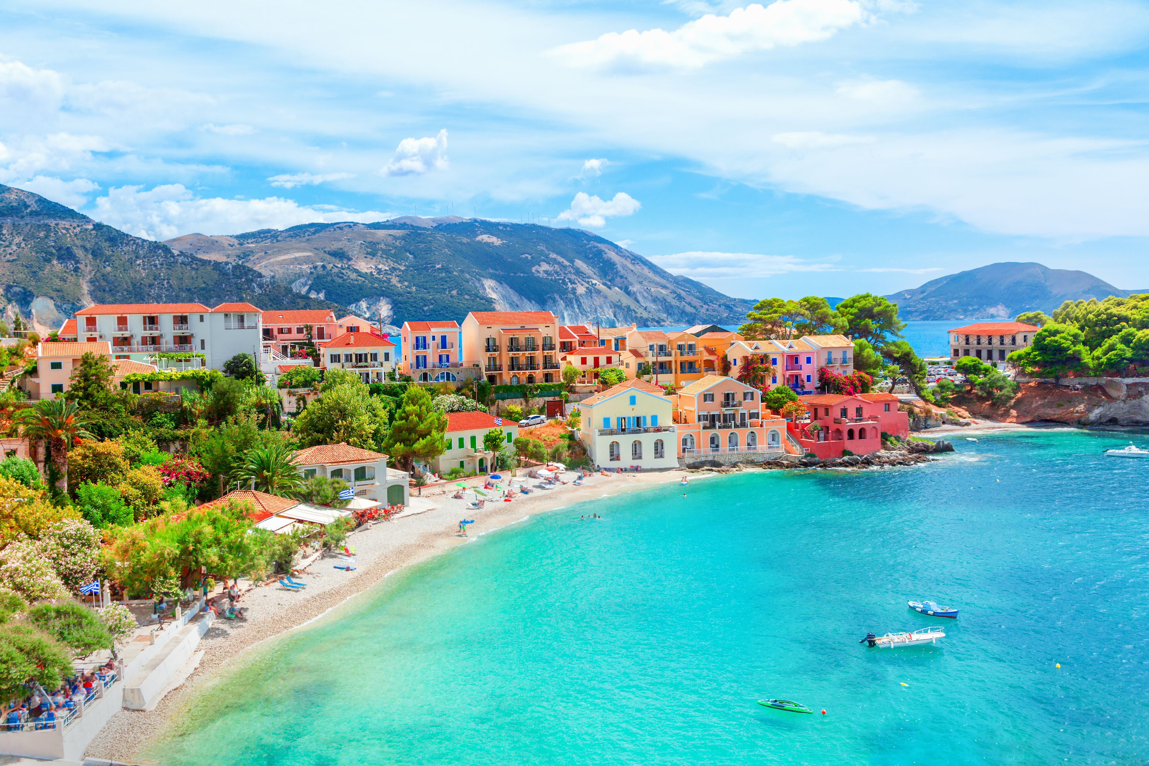A picture of the colour village of Assos in Kefalonia, with traditional houses along the bay showing a sandy beach and clear blue water
