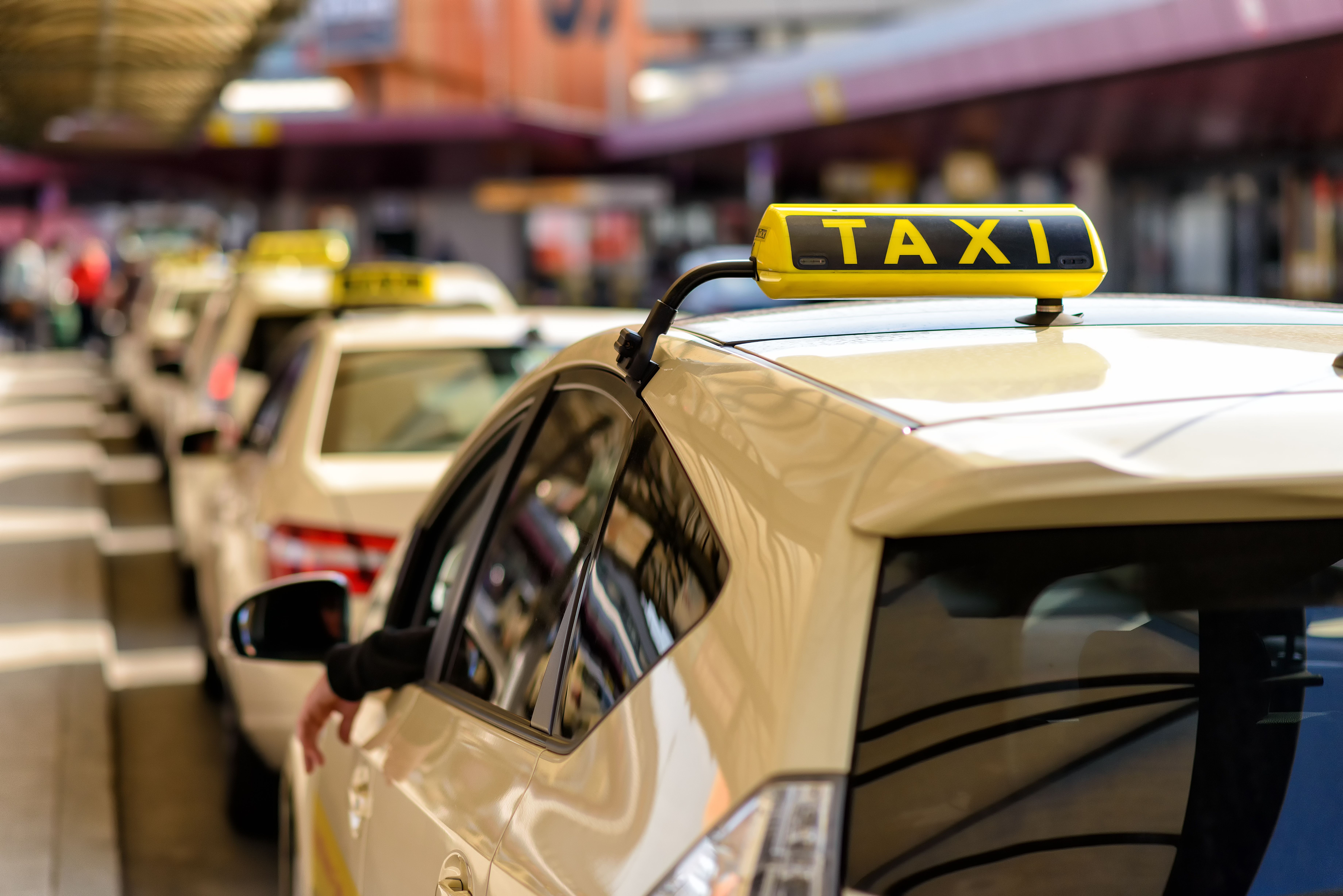 Close up image of a line of taxis waiting outside an airport.