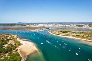Aerial view of the islands and islets off the coast of the Algarve with a flotilla of boats sailing between the Ria Formosa Natural Park and Tavira Island