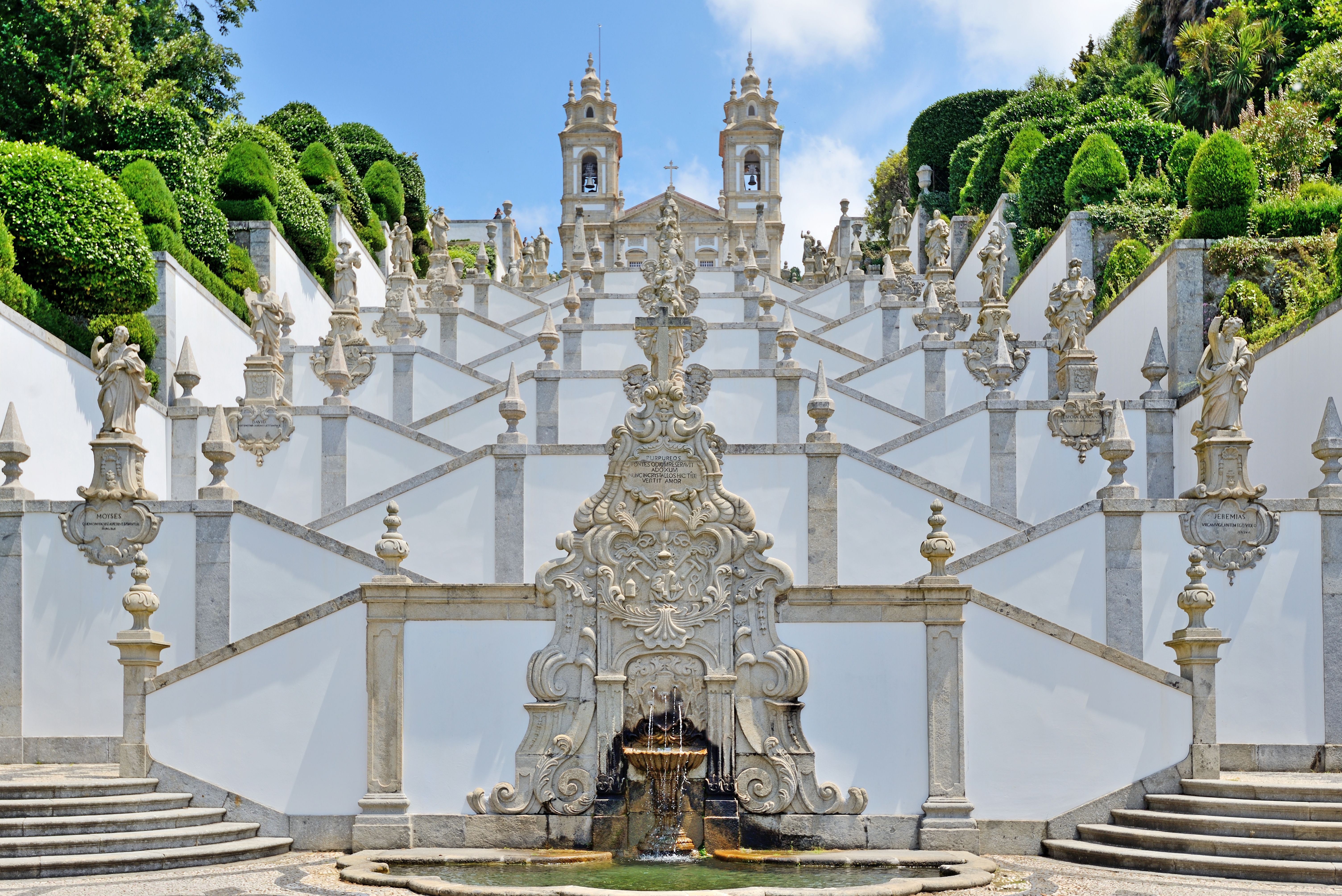 View from the base of a monumental baroque stairway leading up to a whitewashed church.