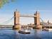 View of the two-towered Tower Bridge spanning the Thames in London with boat tours running in the river