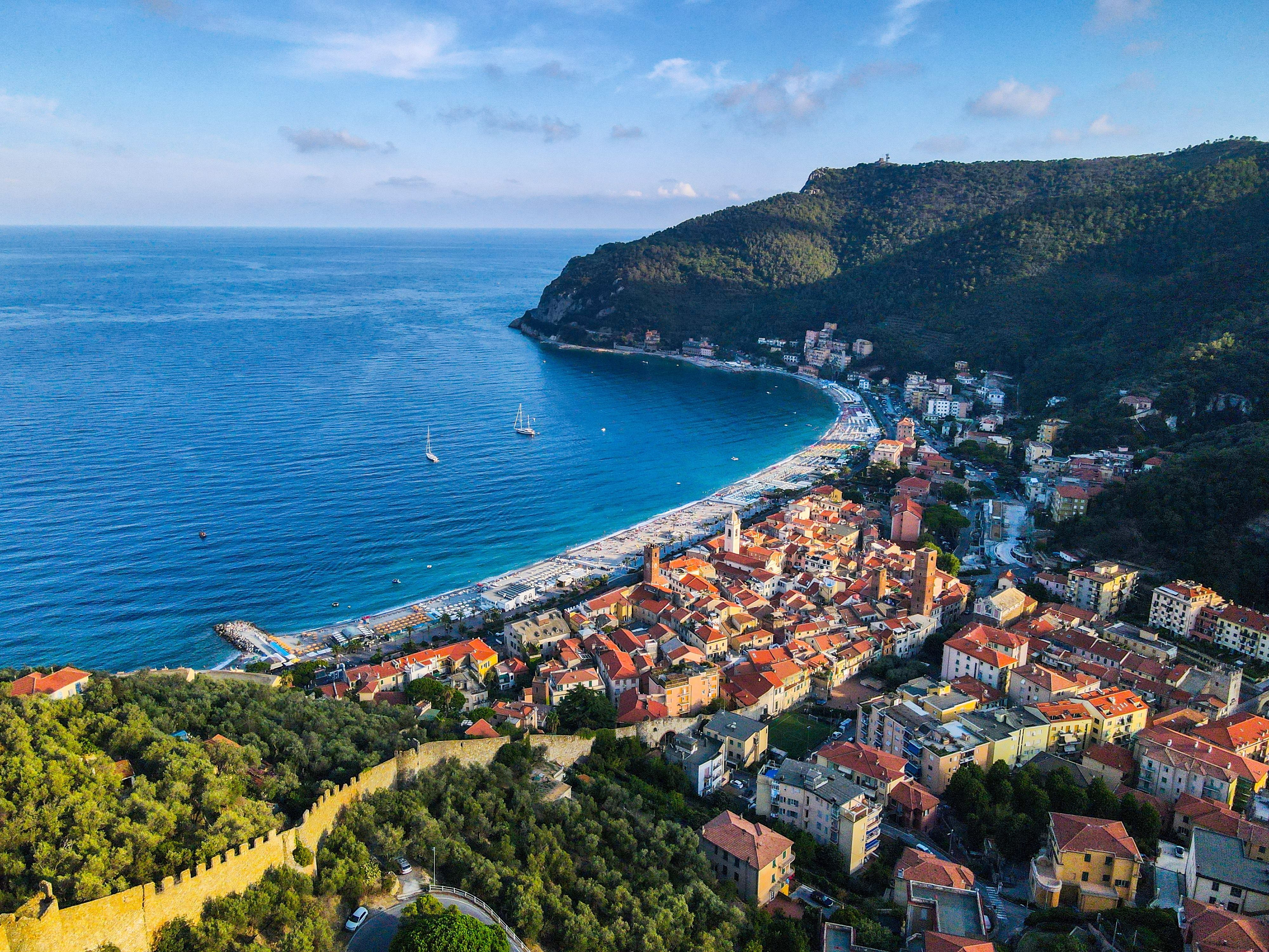 Aerial view of a beautiful seaside village tucked between tree-covered cliffs and with a huge sweep of a beach