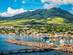 A view of St Kitts Island in the Caribbean with a rock spit bank harbouring colourful fishing boats and lush green mountains in the background