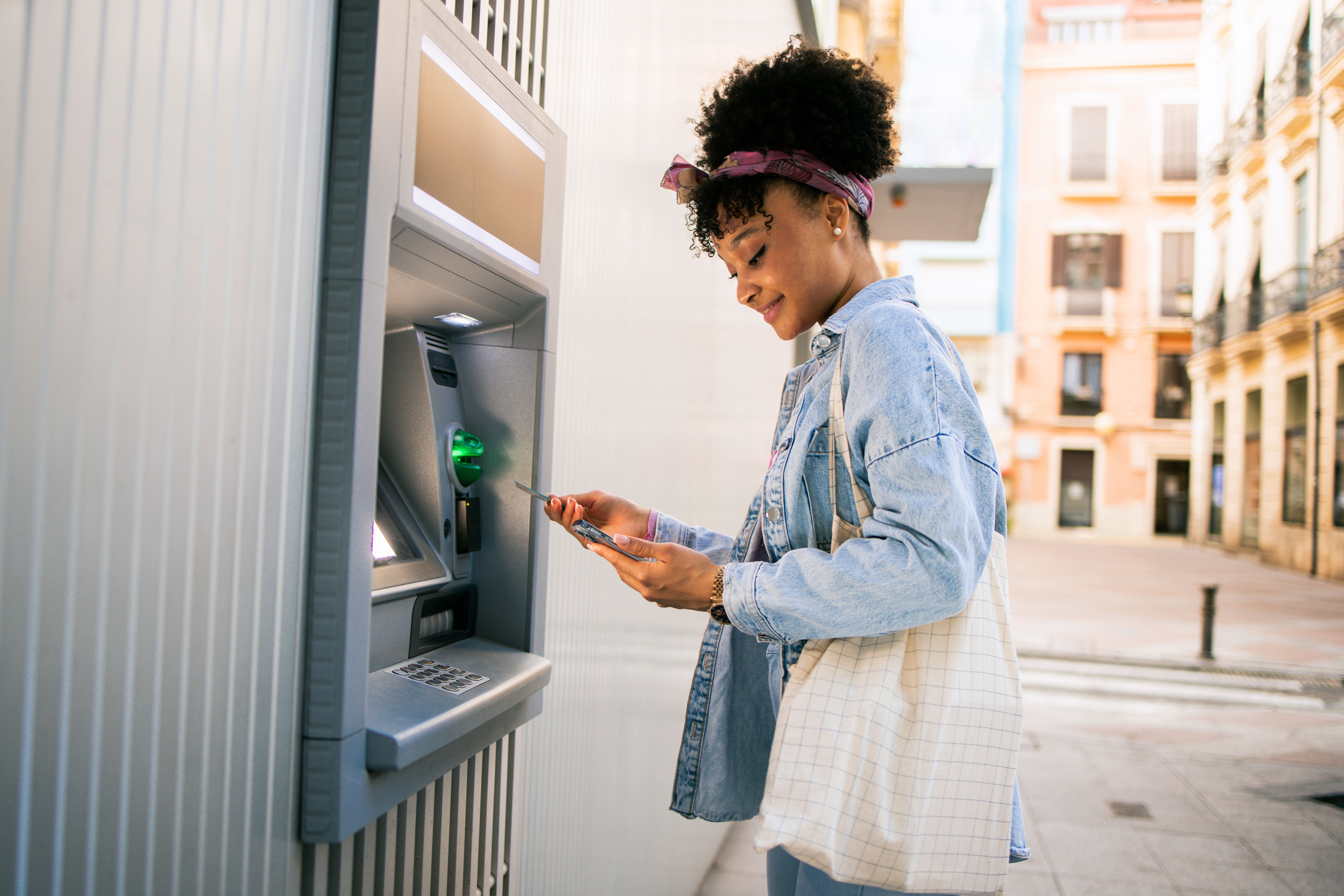 A woman making a withdrawal at an ATM machine using her credit card