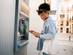 A woman making a withdrawal at an ATM machine using her credit card