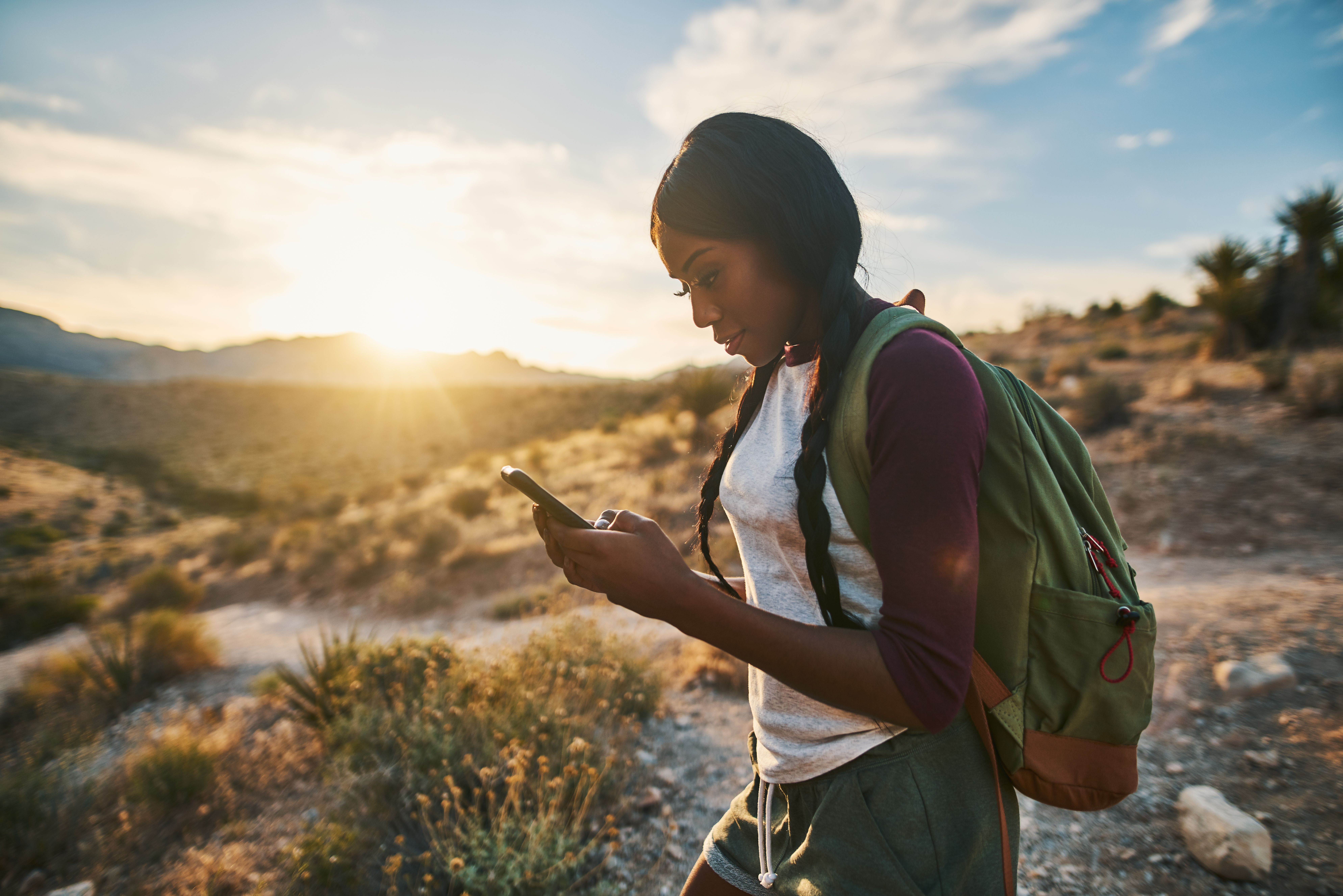 Woman with backpack looking at smart phone while hiking in Red Rock Canyon Nevada