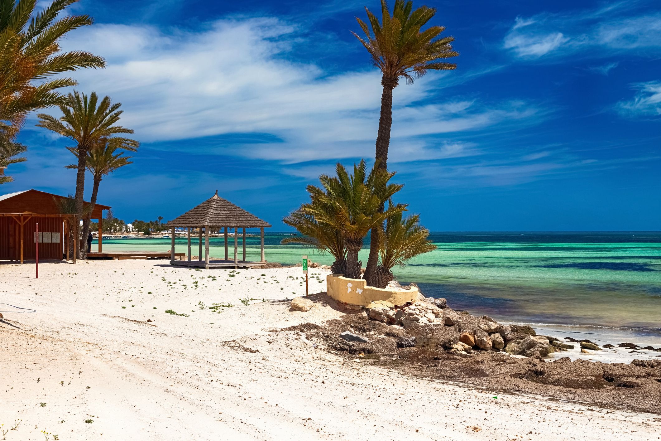 A view of the Mediterranean coast with white sand beach and palm trees in Djerba, Tunisia