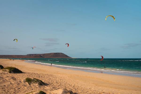 View of kitesurfers on a long and flat sandy beach on a cloudless day in Cape Verde
