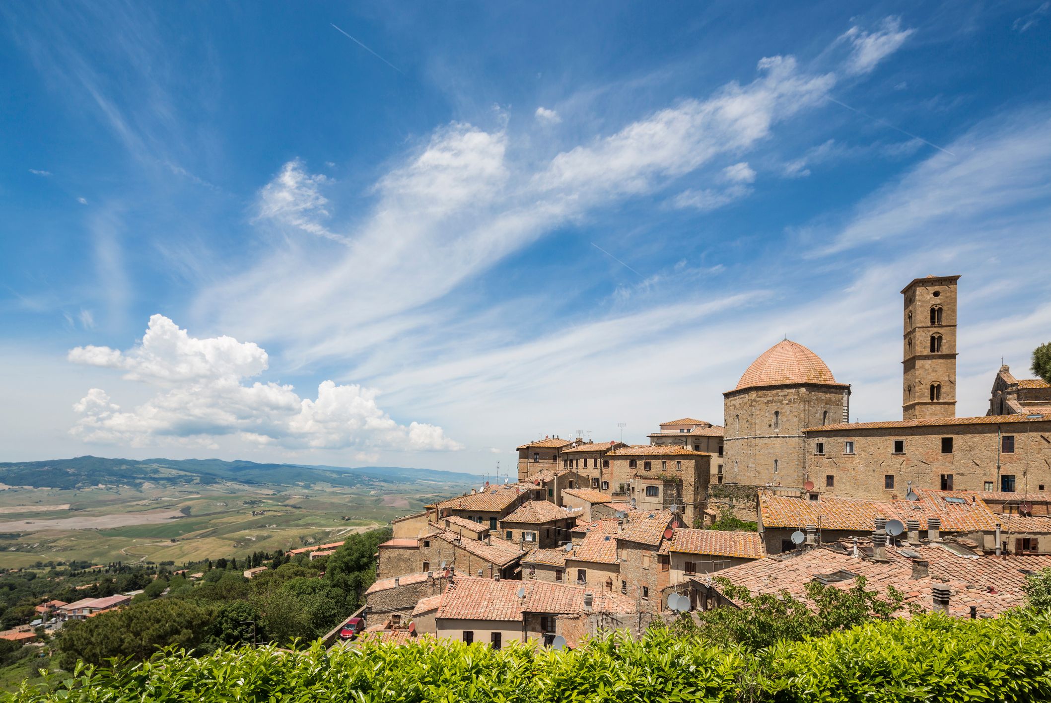 Looking out over the stone buildings and domed cathedral of Volterra with a green valley below