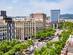 View of the Main Street in Gracia, Barcelona lined by high-rise buildings and green trees