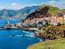 View of a coastal town with whitewashed houses with red roofs surrounded by green mountains