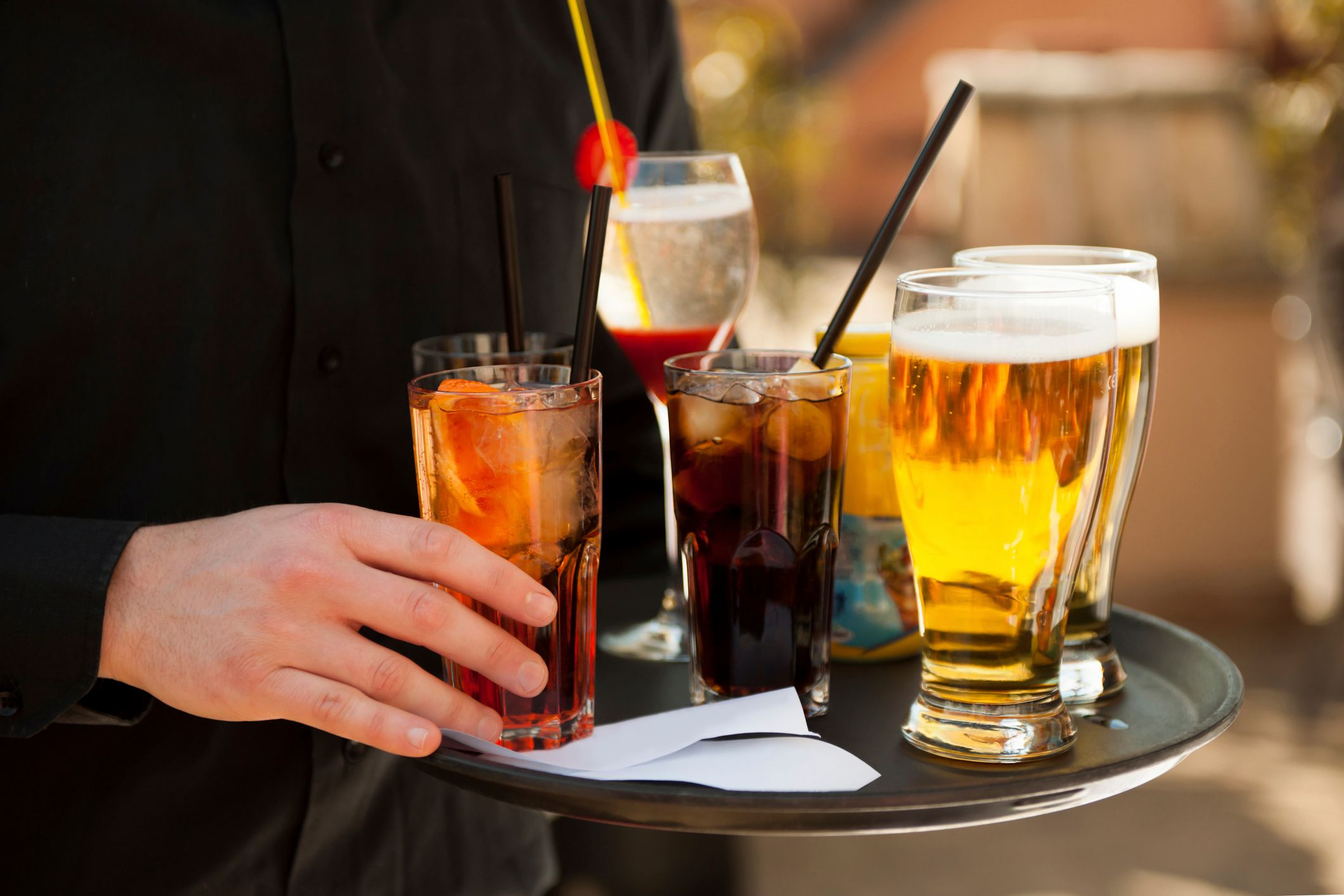 A waiter carrying an assortment of alcoholic drinks on a tray