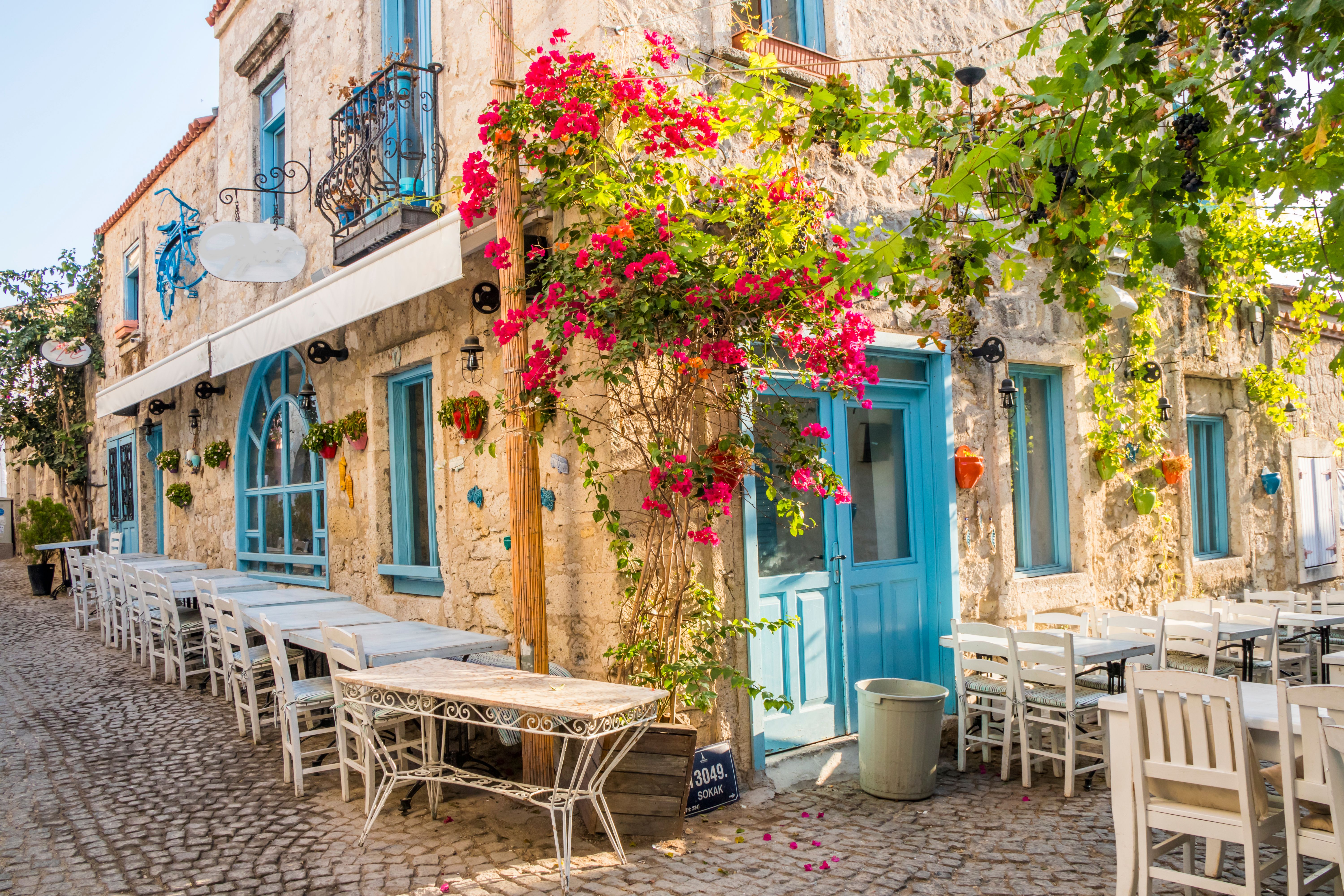 Traditional stone houses with blue shutters in the town of Alacati in Turkey