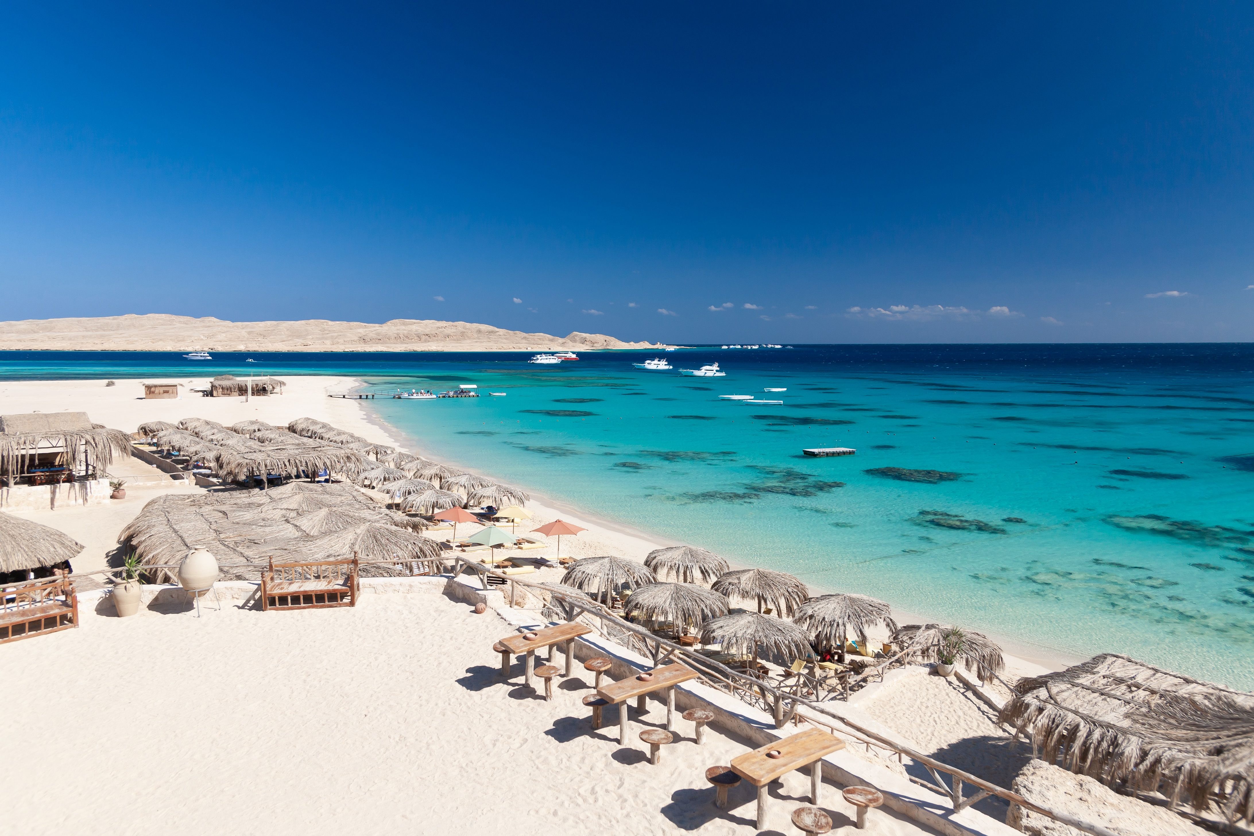 A white sand beach with straw umbrellas in Hurghada, Egypt