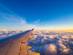 A view from the right side window of an plane showing the aircraft wing during a sunrise over the clouds