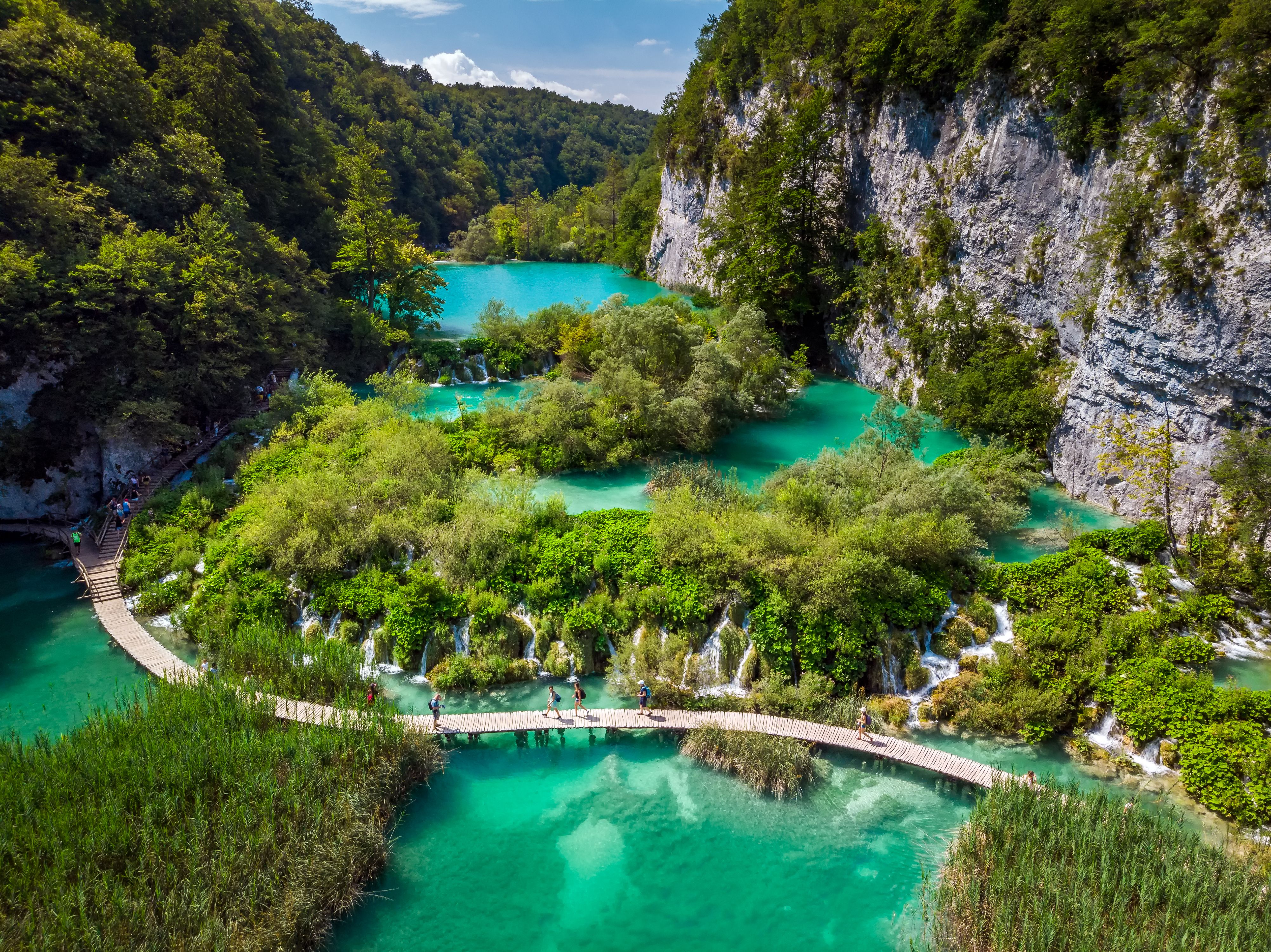 A view of a wooden walkway through the lakes and waterfalls of Plitvice Lakes National Park in Croatia