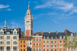 A skyline view of traditional colourful buildings and the tower of the Chamber of Commerce in Lille, France with bright blue sky