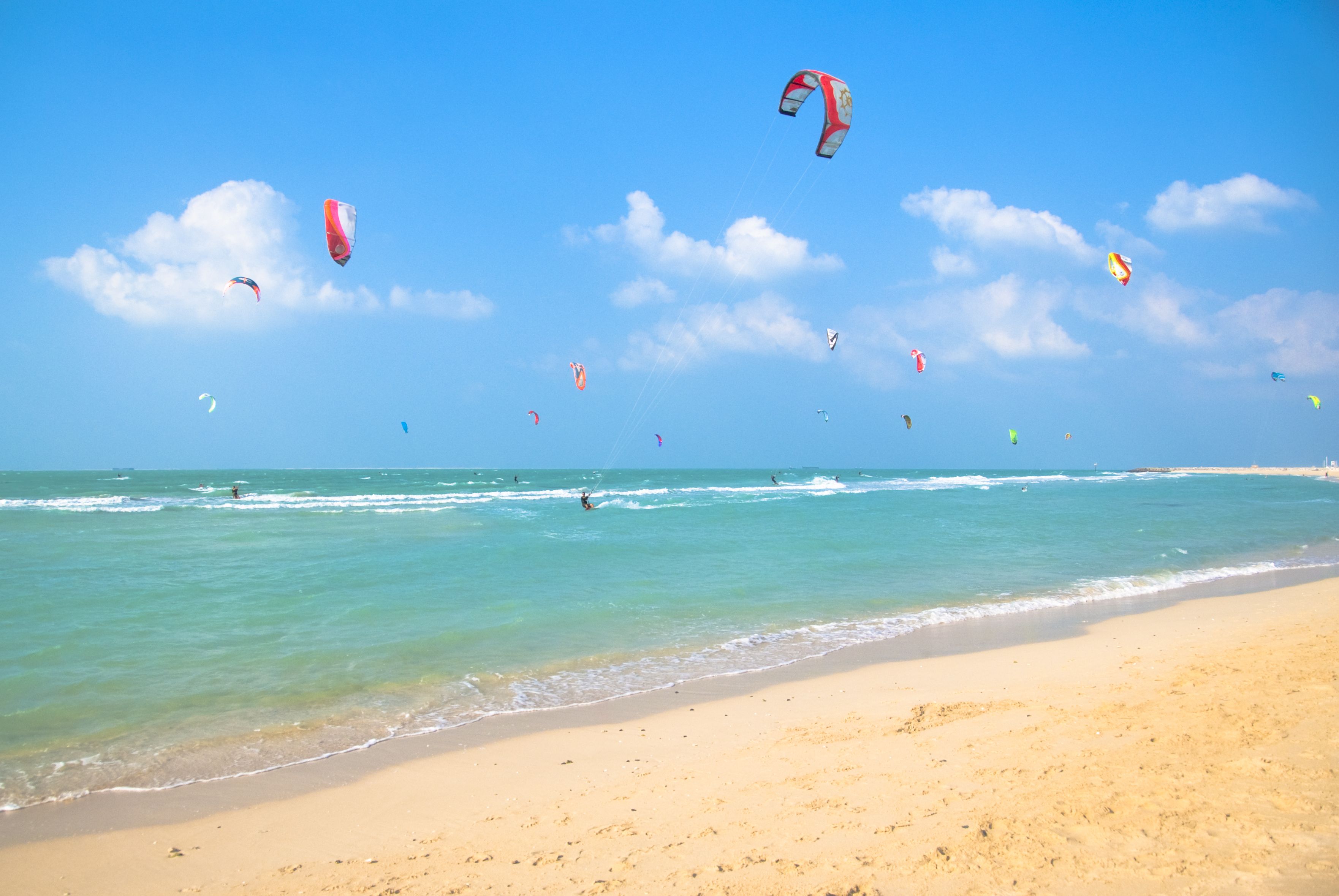 A view of kite surfers with colourful sails in the sea at Kite Beach, Dubai