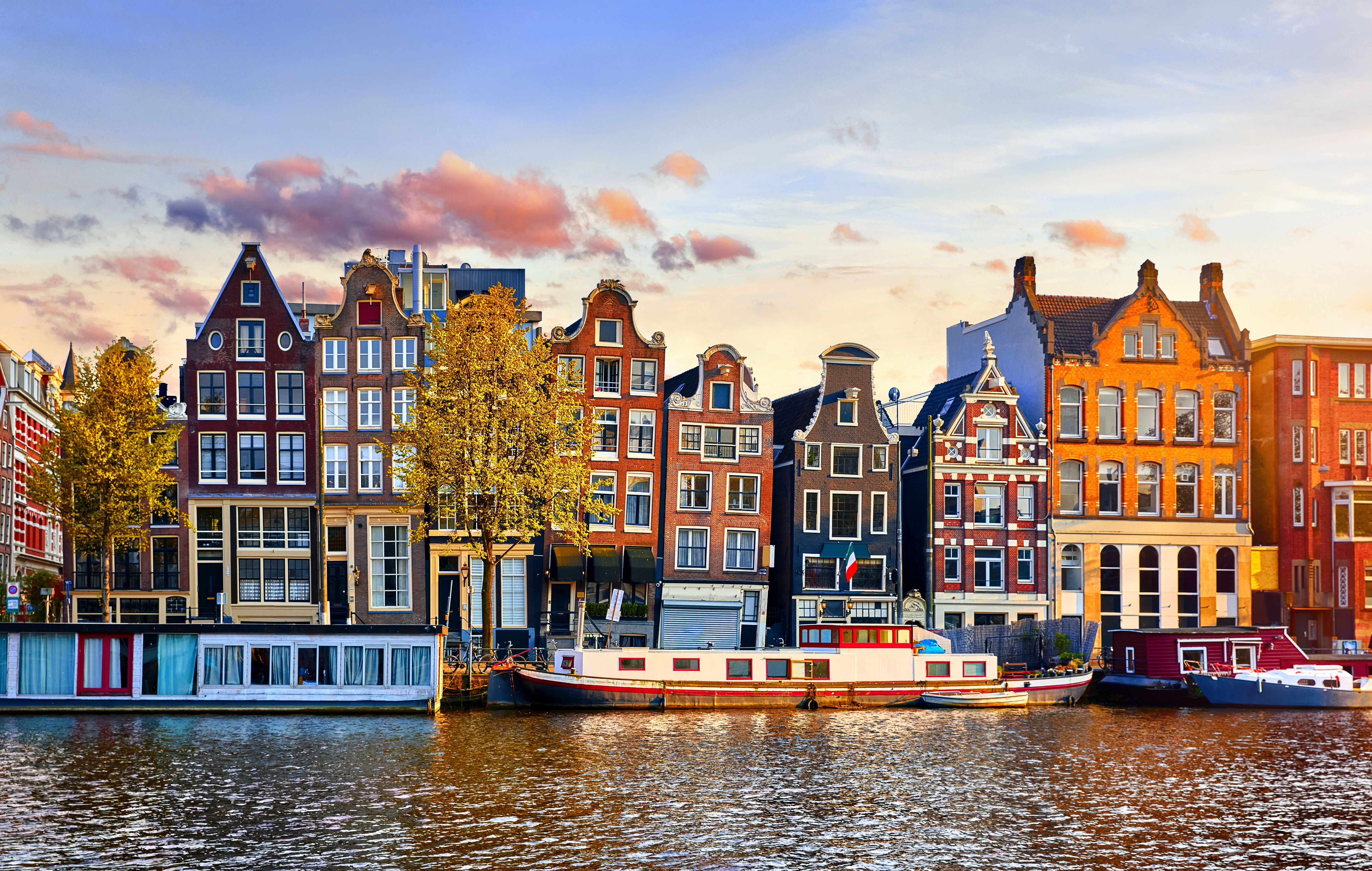 The crooked 'Dancing Houses' in traditional Amsterdam style along the Damrak canal in Amsterdam at sunset