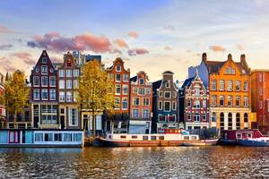 The crooked 'Dancing Houses' in traditional Amsterdam style along the Damrak canal in Amsterdam at sunset