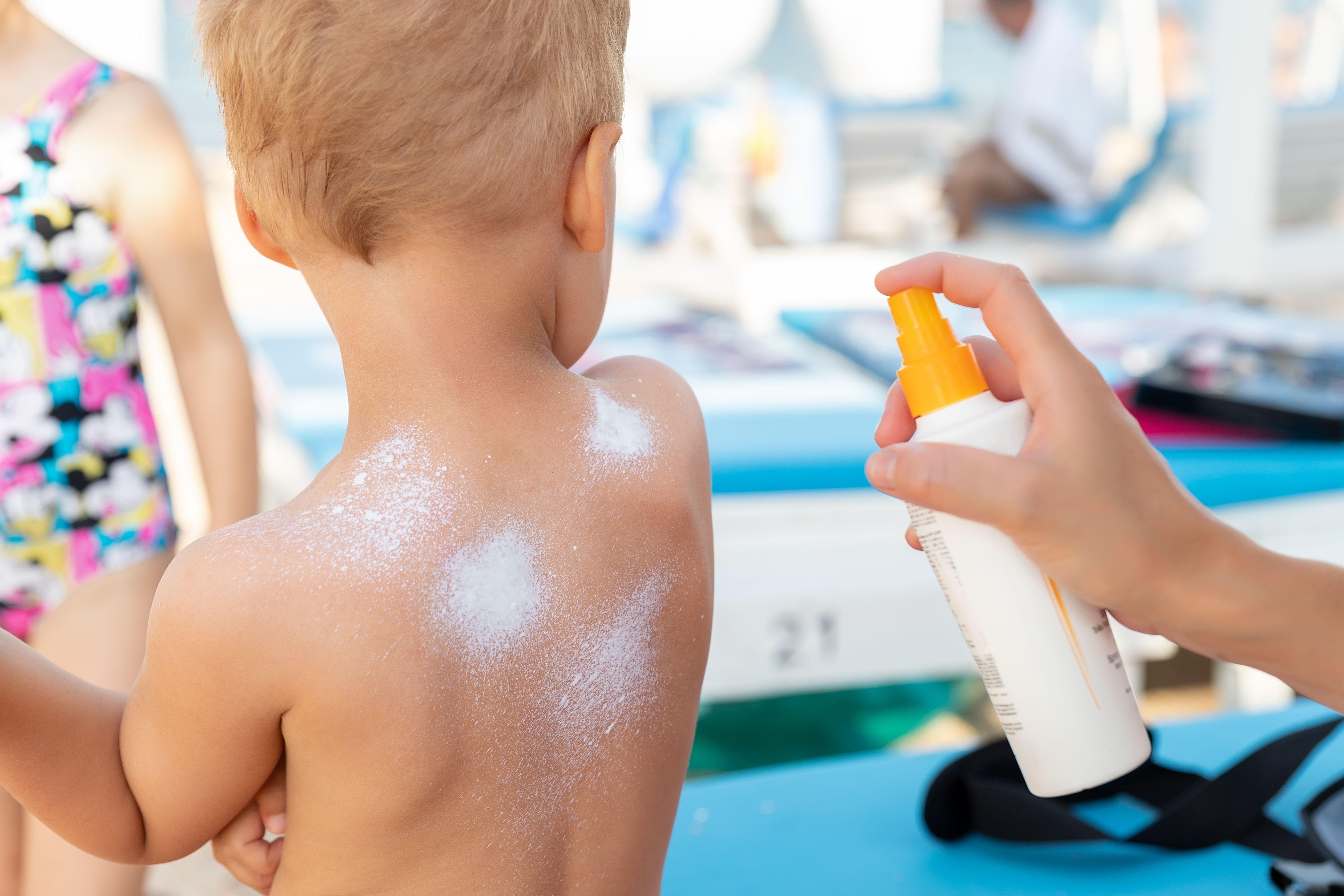 Sun cream being sprayed on a child at the beach