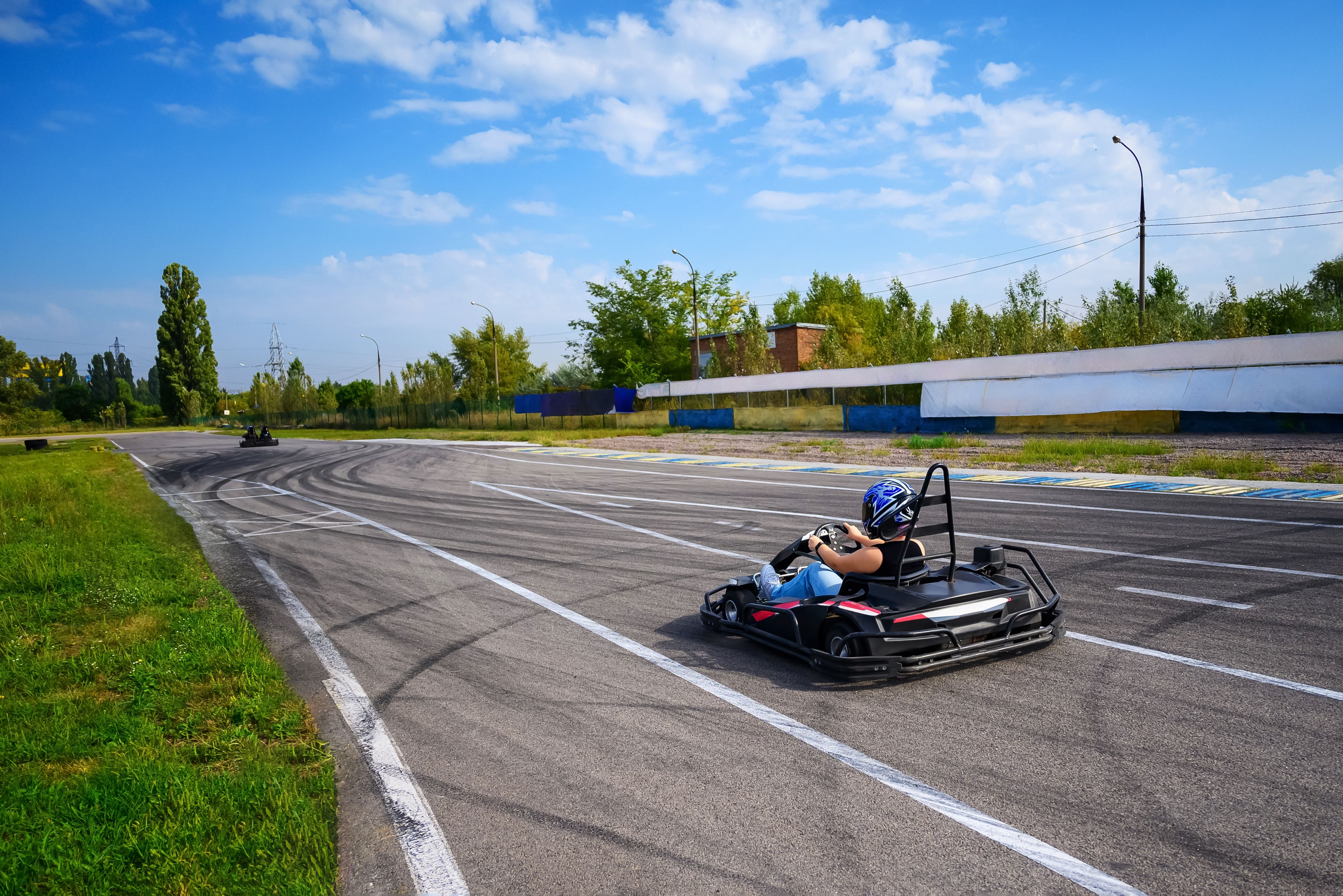 Racer driving a go-kart on an outdoor race track on a bright sunny day